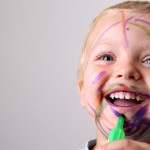 Laughing Toddler playing with colored pens making a mess