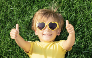 Child on grass in summer with sunglasses on